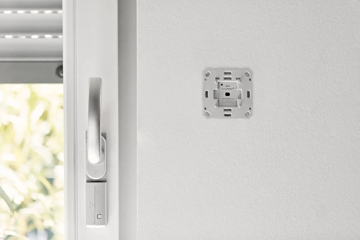 Homematic IP Rollladenaktor neben einem Fenster mit teilweise geschlossenem Rollladen